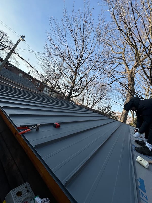 Charcoal standing-seam metal roof panels mid-installation